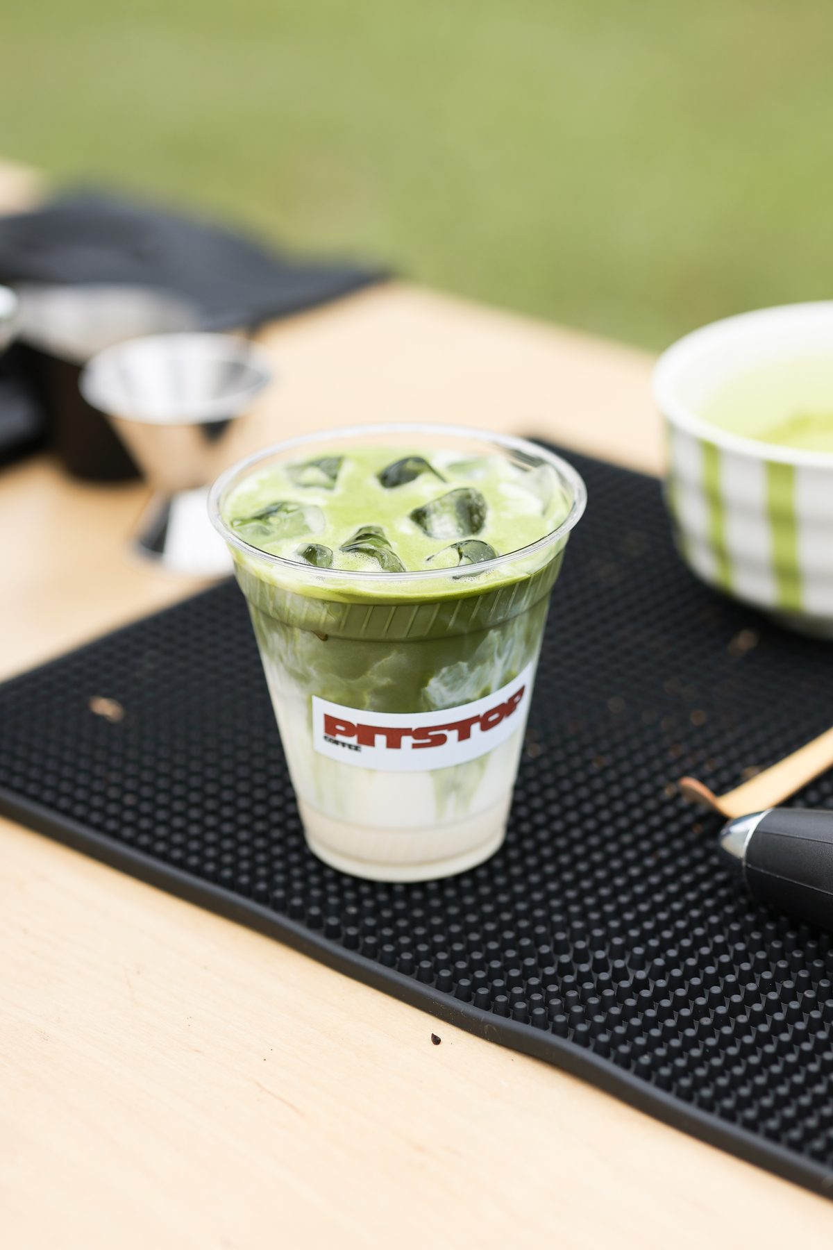 An iced matcha latte in a Pit Stop branded cup